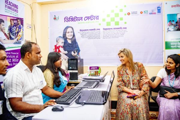 During a July 2019 country visit to Bangladesh, the UNSGSA speaks with users and agents of a2i's new integrated digital platform known as ekPay, as well as ekShop, the latter of which enables a2i to facilitate entrepreneurship online.  Photo credit: Robin Utrecht