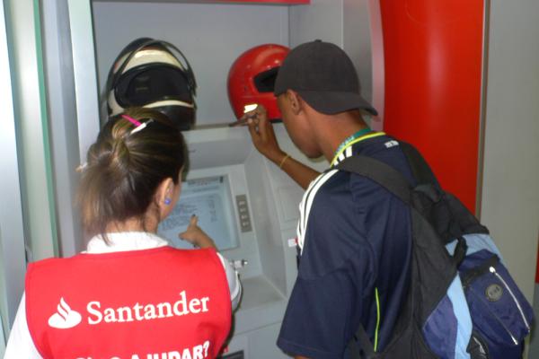 ATMs serve clients conveniently and at low cost. As part of client outreach, this bank has a staff member available to assist to help new customers learn about how to use the ATM. (Compelexo do Alemão, Rio de Janeiro, Brazil. May 2012) - Photo credit: Amina Tirana